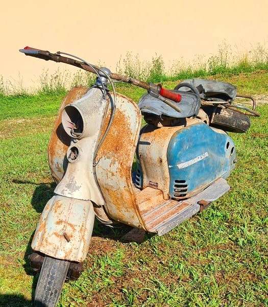 Épave ancienne de scooter hors d'usage dans le jardin