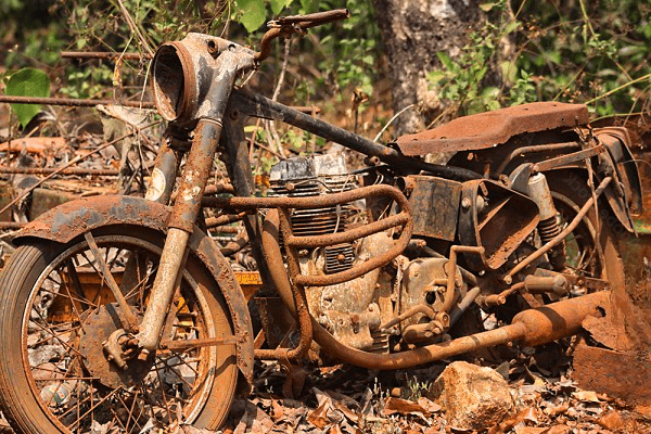 Une vieille épave de moto rouillée abandonnée dans la forêt